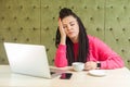 Portrait of tired kind beautiful young freelancer woman with black dreadlocks hairstyle in pink blouse is sitting in cafe and fall Royalty Free Stock Photo