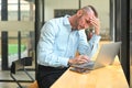 Overworked adut man office worker holding her head in hands, feeling distressed anxious with work deadline