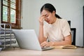 Overworked Asian female woman feeling tired working with laptop, focusing oh her work Royalty Free Stock Photo