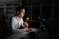 Overworked businessman eating tasty burger while working in office at night. Handsome professional male employee sitting Royalty Free Stock Photo