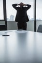 Overworked businessman with hands behind his head looking out the window at the city Royalty Free Stock Photo