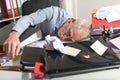 Overworked businessman sleeping on a messy desk Royalty Free Stock Photo