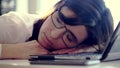 Overworked, Exhausted and tired young businesswoman with glasses, resting, sleeping over a laptop in a desk at work in Royalty Free Stock Photo