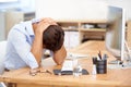 Overworked and exhuasted. an overworked businessman hunched over his desk in front of his computer.