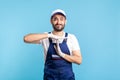 Overworked handyman in overalls and gloves showing time out gesture, need break. Profession of service industry Royalty Free Stock Photo