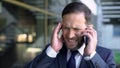 Overworked male manager talking on phone, suffering from migraine, headache Royalty Free Stock Photo