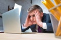 Overworked mature businessman looking at laptop on desk in office Royalty Free Stock Photo