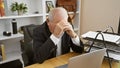 Overworked senior man feeling stressed, working on laptop at office Royalty Free Stock Photo