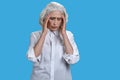 Overworked senior woman suffering from headache against blue background. Royalty Free Stock Photo