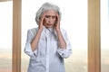 Overworked senior woman suffering from headache. Office window in the background. Royalty Free Stock Photo