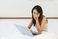 Overworked tired Asian woman rubbing her nose bridge and closing eyes on bed. Girl feel eye strain fatigue after computer work and Royalty Free Stock Photo