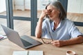 Overworked tired old lady holding glasses feeling headache after computer work. Royalty Free Stock Photo