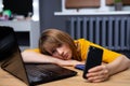 Overworked tired woman. Young exhausted student girl sleeping in office. Woman using laptop, smartphone at home office. Royalty Free Stock Photo