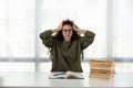 Overworked. Tired young lady sit at home desk crowded with books hide face in palms feeling headache migraine. Exhausted female Royalty Free Stock Photo