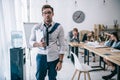 overworked untidy businessman with clipboard standing at office while colleagues sitting