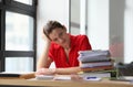 Overworked woman sitting at table littered with papers Royalty Free Stock Photo