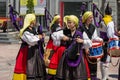 Local music group of male and female bagpipers and drummers dressed in traditional clothes play at a city square.