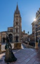 View of the La Regenta statue and San Salvador Cathedral in the historic city center of Oviedo with a sunburst