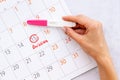 Ovulation home test in female hand over calendar with red mark