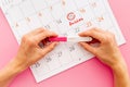 Ovulation home test in female hand over calendar with red mark