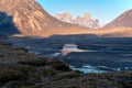 Wild river winds through remote, stony arctic landscape. A big moraine and iconic mountains on the horizon. Mt. Asgard