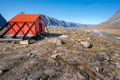 Owl River emergency shelter in remote arctic wilderness with a backpack in front of it . Sunny day in Akshayuk Pass