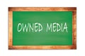 OWNED MEDIA text written on green school board