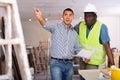 Owner of apartment indicates to worker in yellow vest where to start repairing room