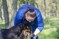 Owner in blue tracksuit examines dog`s paw outdoors