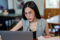 Owner of the cafe, beautiful young Asian woman wearing glasses. just looking at the laptop Examine pile of documents laying beside