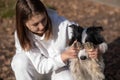 The owner closes the eyes of the border collie dog with his paws.