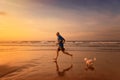 Owner and dog are running at the beach in sunset time Royalty Free Stock Photo