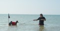 Owner is playing with his pets. Man in sea drags raft tied to a rope, on which two funny dachshund dogs in privateer