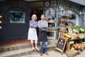 Owners Standing Next To Produce Display At Deli