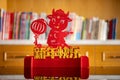 Ox mascot with lantern in front of a books shelf in a living room as symbol of Chinese New Year of the Ox 2021 translation of