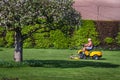 Senior citizen riding lawn mower in a garden Royalty Free Stock Photo