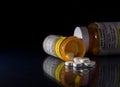 Macro of oxycodone opioid tablets with prescription bottles against dark background