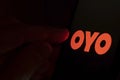 OYO hotel booking app logo on the screen and finger pointing at it. Concept photo