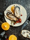 Oysters heart shape in plate with lemon, cranberries, microgreens, knife, shells on marble