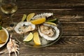 Oysters in a plate with ice and lemon, with a glass of white dry wine on a wooden background. Seafood, restaurant, exquisite taste Royalty Free Stock Photo