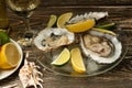 Oysters in a plate with ice and lemon, with a glass of white dry wine on a wooden background. Seafood, restaurant, exquisite taste Royalty Free Stock Photo