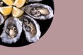 Oysters plate with lemon on powdery pink background.
