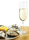 Oysters in a white plate with lemon and a glass of wine on a wooden table