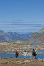 Hikers walk on paths over the lakes of Grandes Rousses mountain range