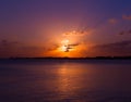 Purple Golden yellow sunset over the sea ocean water with clouds and sun in the sky and reflection in the water with fisherman