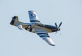 A P-51 Mustang fighter banks right in a clear blue sky