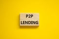 P2P peer to peer lending symbol. Concept words P2P lending on wooden blocks on a beautiful yellow background. Business and P2P