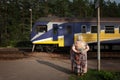 PABAZI, LATVIA - AUGUST 21, 2023: Selective blur on an old woman, senior, observing a suburban regional train of LDZ Latvijas