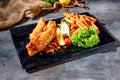 Pacific Dory fish steak with fries and salad in dish side top view on dark background Royalty Free Stock Photo
