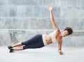 Pacific islander athlete girl with afro performing exercising routines plank with twist, one hand raised